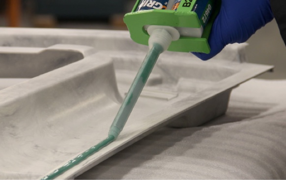 bead of adhesive being applied to edge of finished composite part