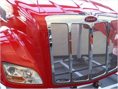 red heavy truck front end with chrome colored grill made from composite materials